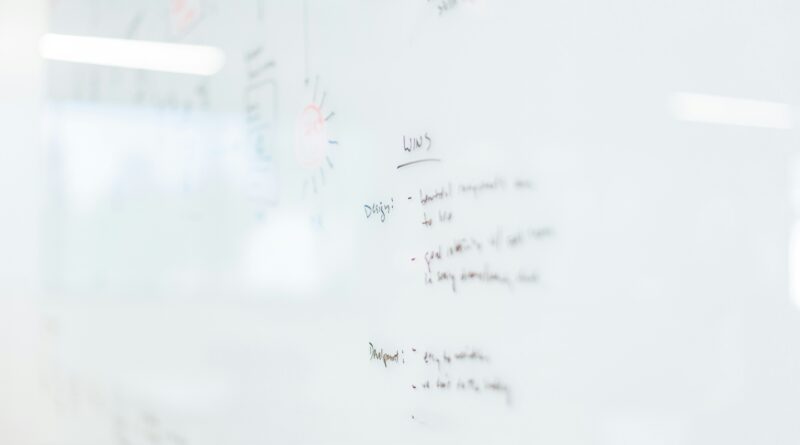 how to clean a whiteboard showing microfibre cloth and isopropyl alcohol spray being used to remove ghost marks and dried marker ink from a white dry erase board surface