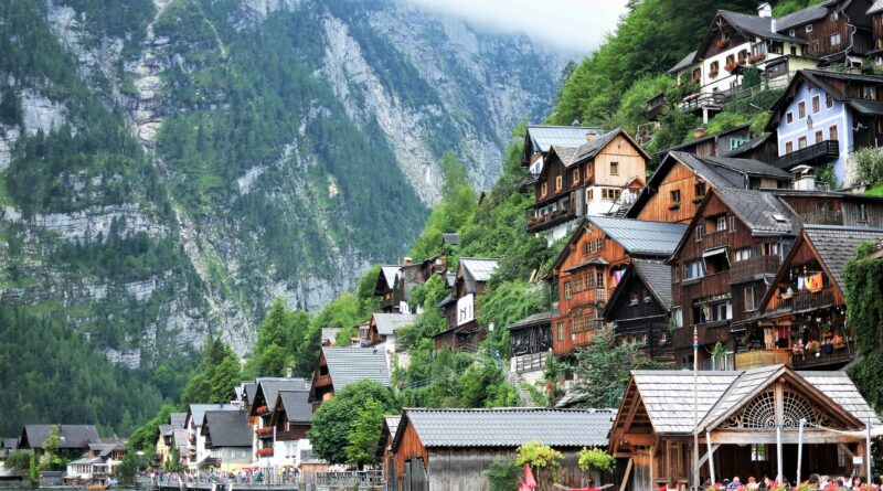 Hallstatt Austria village reflected in the clear blue waters of Lake Hallstatt with Dachstein Mountains in the background at sunrise