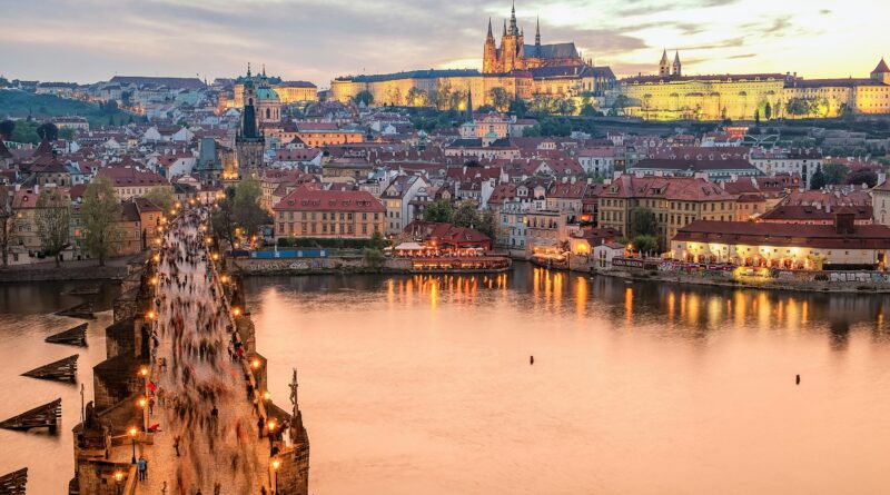 things to do in Prague showing Charles Bridge at sunset with baroque statues silhouetted against the Vltava River and Prague Castle in the background